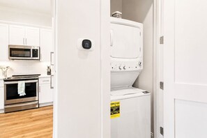 Eine Küche mit weißen Schränken, einer Mikrowelle, einem Backofen und einer Waschmaschine.