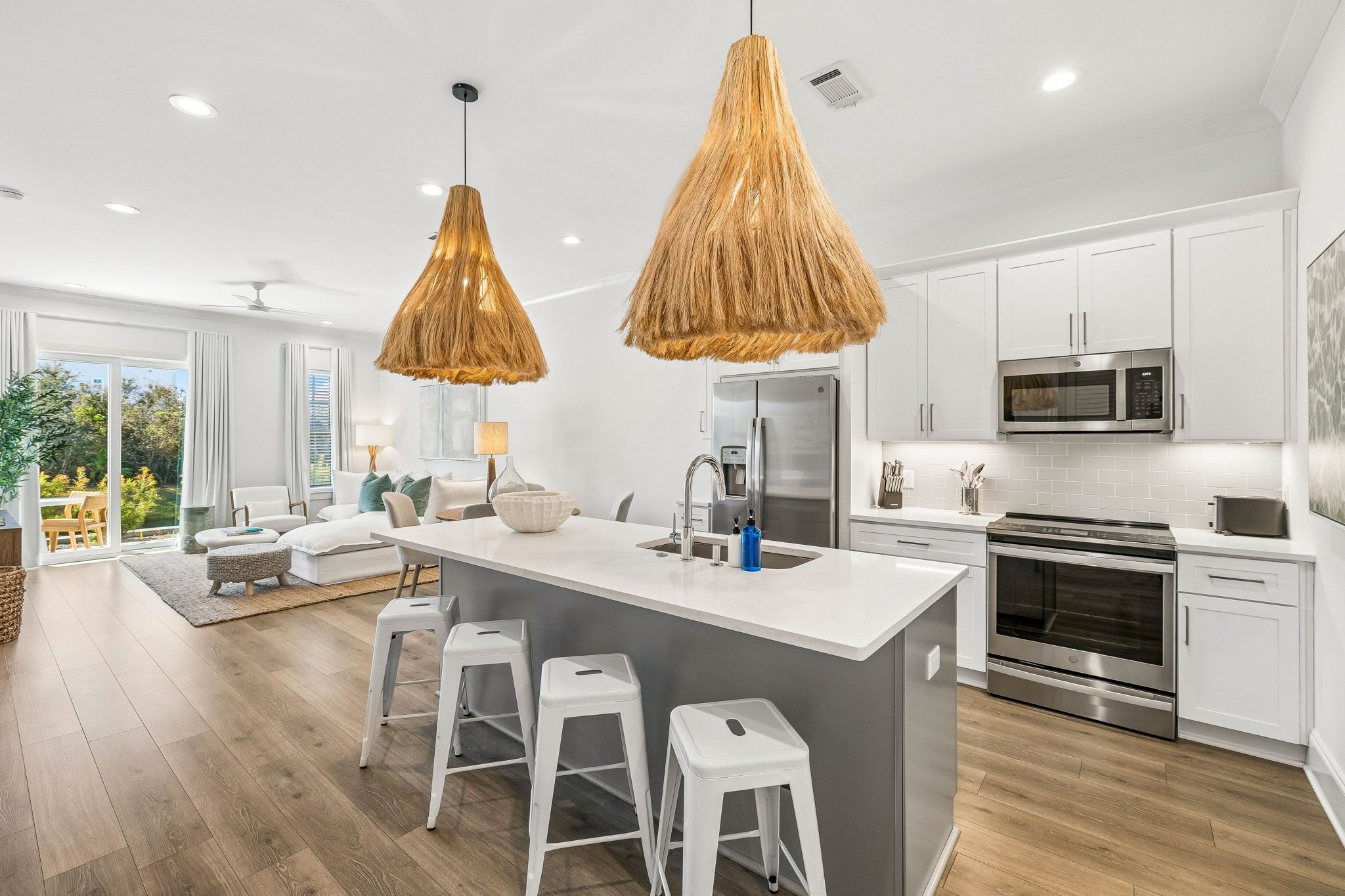 A modern kitchen with white cabinets, stainless steel appliances, and a central island with bar stools.
