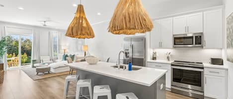 A modern kitchen with white cabinets, stainless steel appliances, and a central island with bar stools.