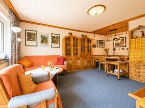 A cozy living room with a sofa, a dining table, and a wooden cabinet. - 4_3 Apartment WildentenNest Zellersee by Interhome (Zell am See)