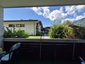 A balcony with a view of a building, greenery, and mountains. - 4_3 Apartment WildentenNest Zellersee by Interhome (Zell am See)