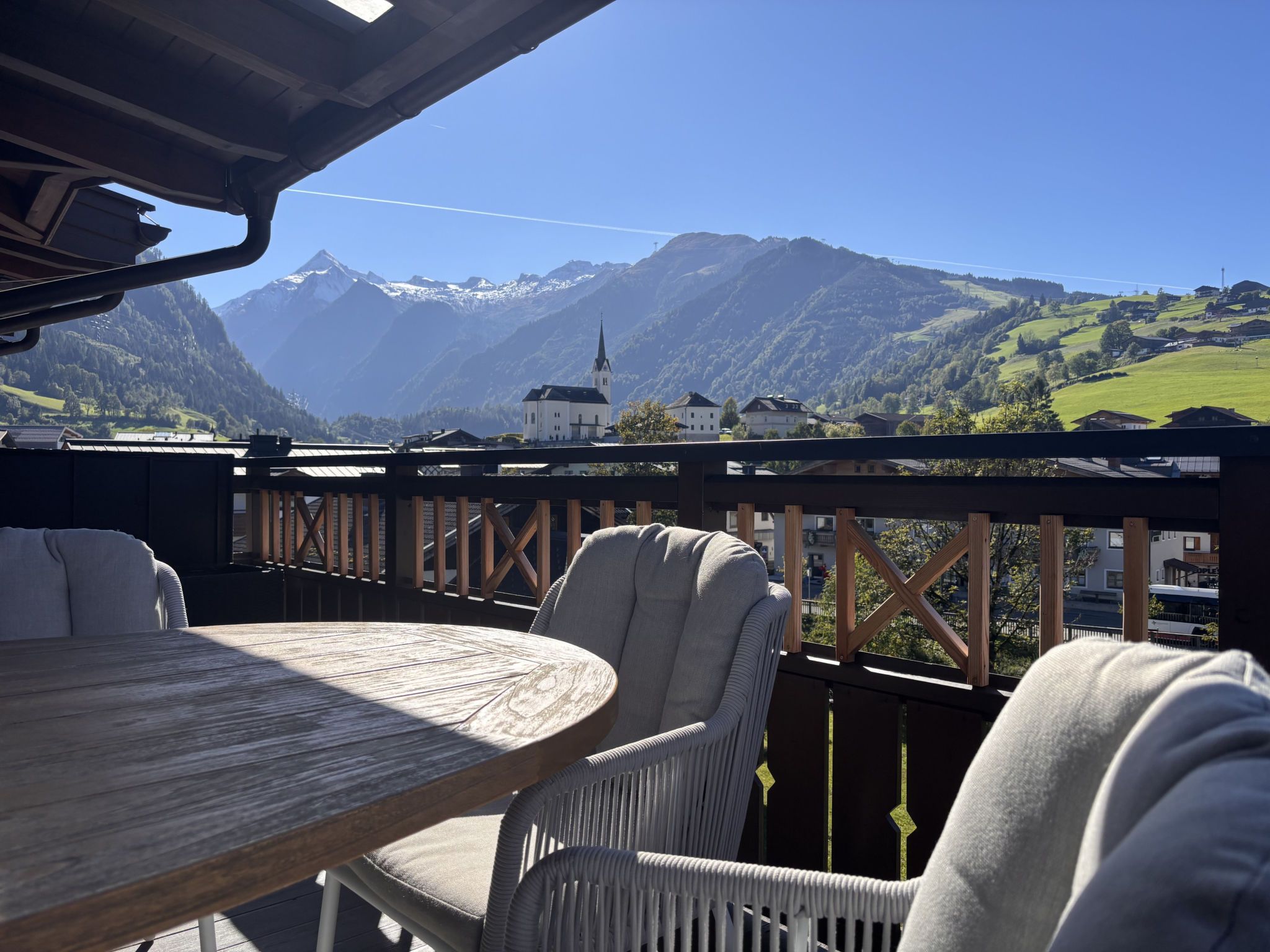 Een terras met uitzicht op bergen, een tafel en twee stoelen.