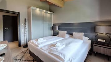 A hotel room with a large bed, a bedside table, a lamp, and a wardrobe.