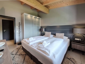Habitación de hotel con una cama grande, una mesita de noche, una lámpara y un armario.