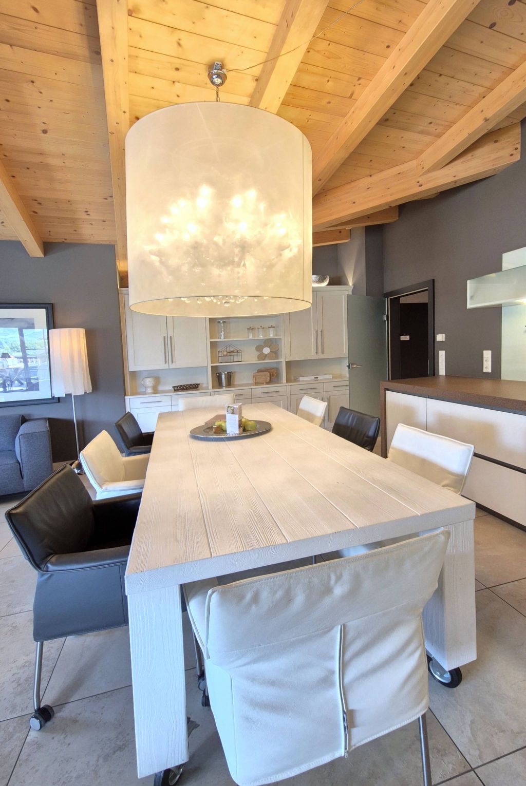A modern kitchen with a large island, white cabinetry, and a hanging light fixture.