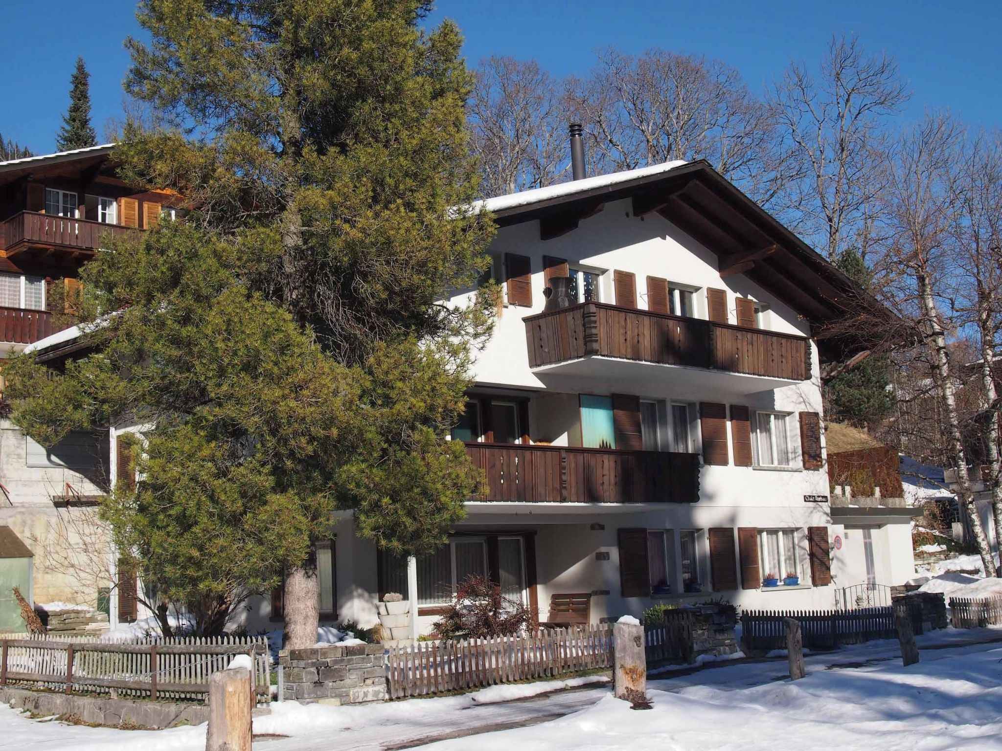 Un immeuble à plusieurs étages, doté de balcons, d’une façade en pierre et d’un sol recouvert de neige.