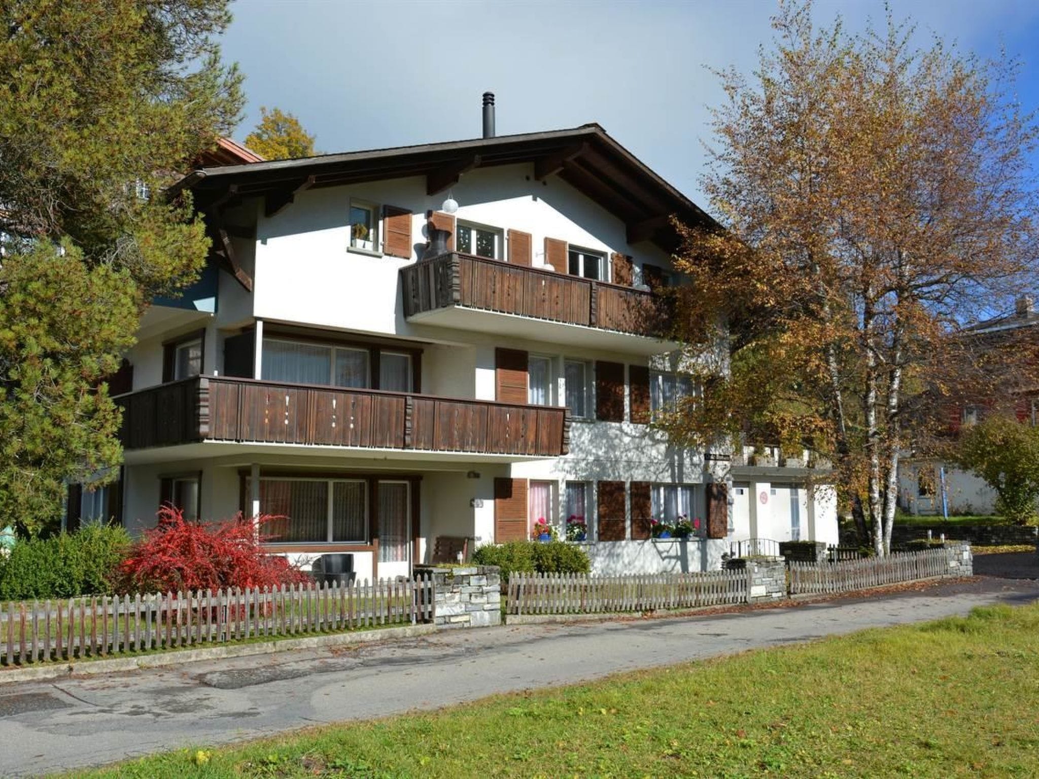 Un immeuble à plusieurs étages, doté de balcons, d’une façade en pierre et d’une clôture en bois.