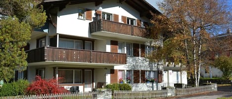 Un immeuble à plusieurs étages, doté de balcons, d’une façade en pierre et d’une clôture en bois.
