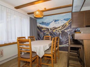 Ein Essbereich mit Tisch und Stühlen, einem Gemälde von einer Berglandschaft und Holzschränken.