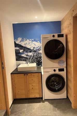A laundry area with a washing machine and dryer, a sink, and a wooden cabinet. - Haus Bettina Appartement/Fewo, Dusche, WC, 4 oder mehr Schlafräume by Interhome (Adelboden)