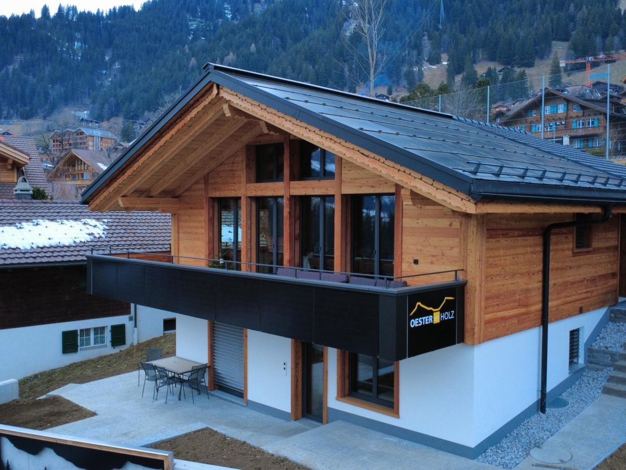 Une maison moderne en bois, dotée d’un balcon, de grandes fenêtres et d’une enseigne indiquant « Oesterholz ».