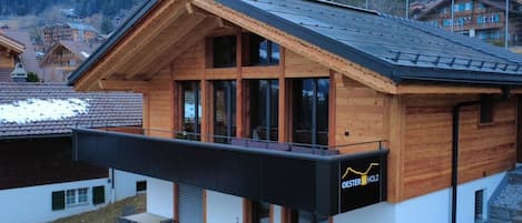 Une maison moderne en bois, dotée d’un balcon, de grandes fenêtres et d’une enseigne indiquant « Oesterholz ».