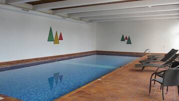 Ein Hallenbad mit gefliestem Boden und Liegestühlen.