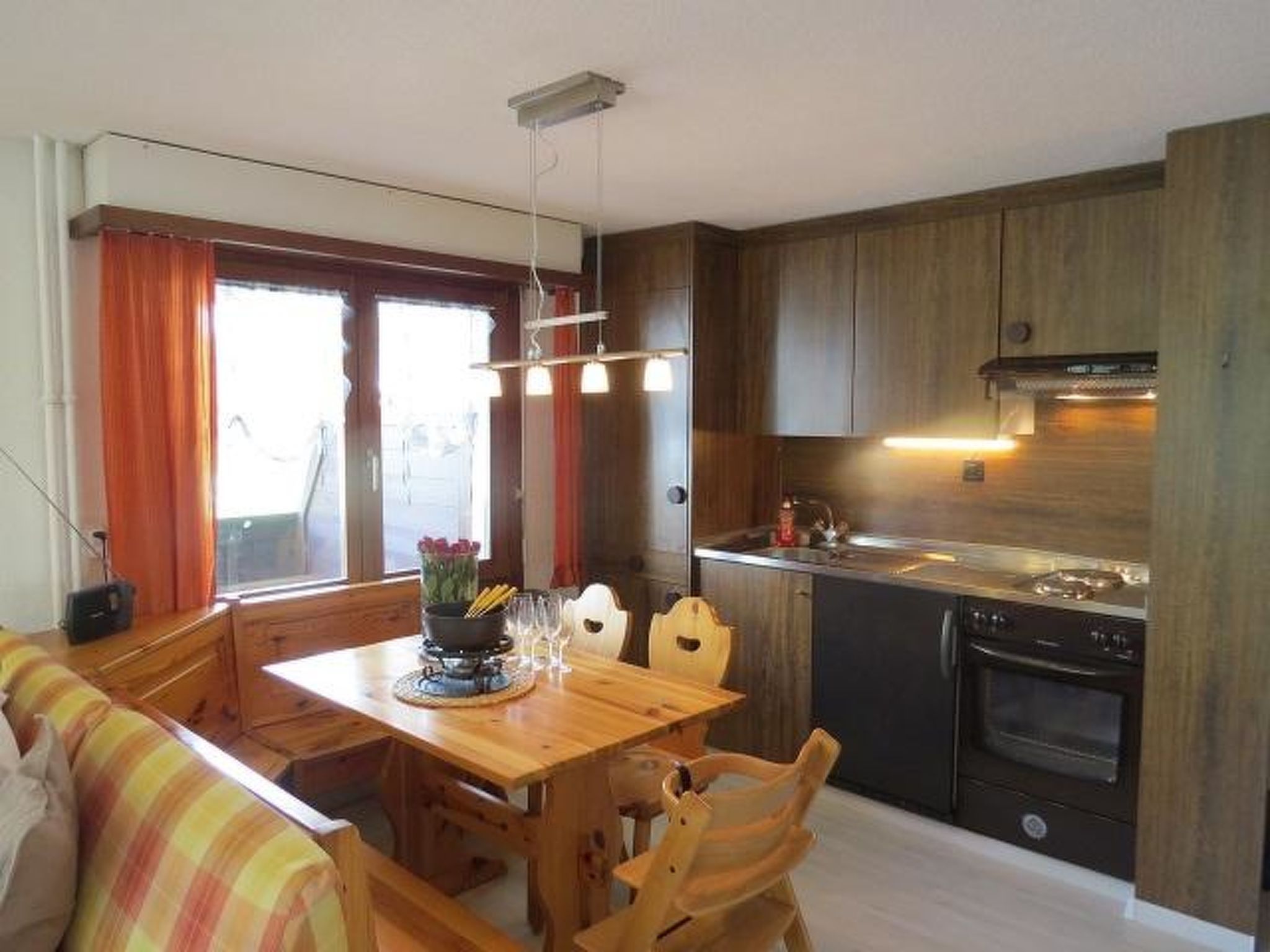 Eine kleine Küche mit Holzausstattung, einem Esstisch mit Stühlen und einem Einbauofen.