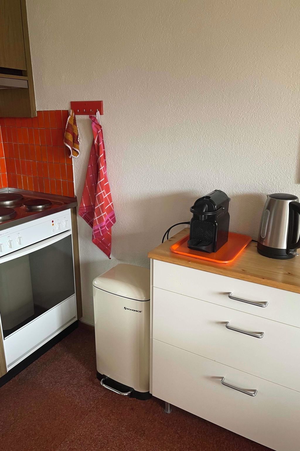 Una kitchenette con estufa, horno y un refrigerador pequeño. Hay una cafetera y una tetera sobre la encimera.