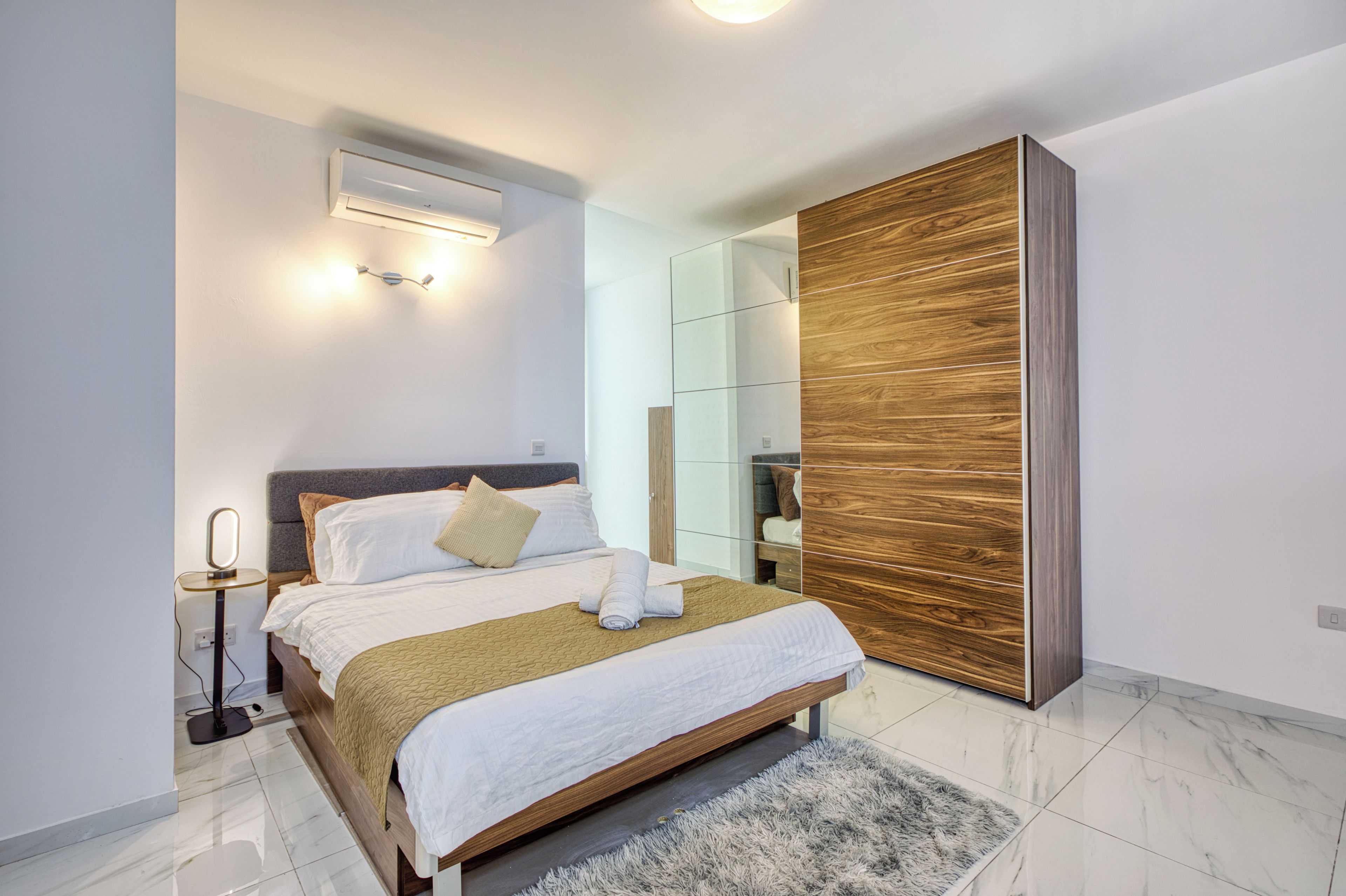 Ein modernes Schlafzimmer mit Bett, Nachttisch und Kleiderschrank.