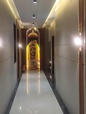 Um corredor com piso espelhado, luminária pendente e parede estampada no final.