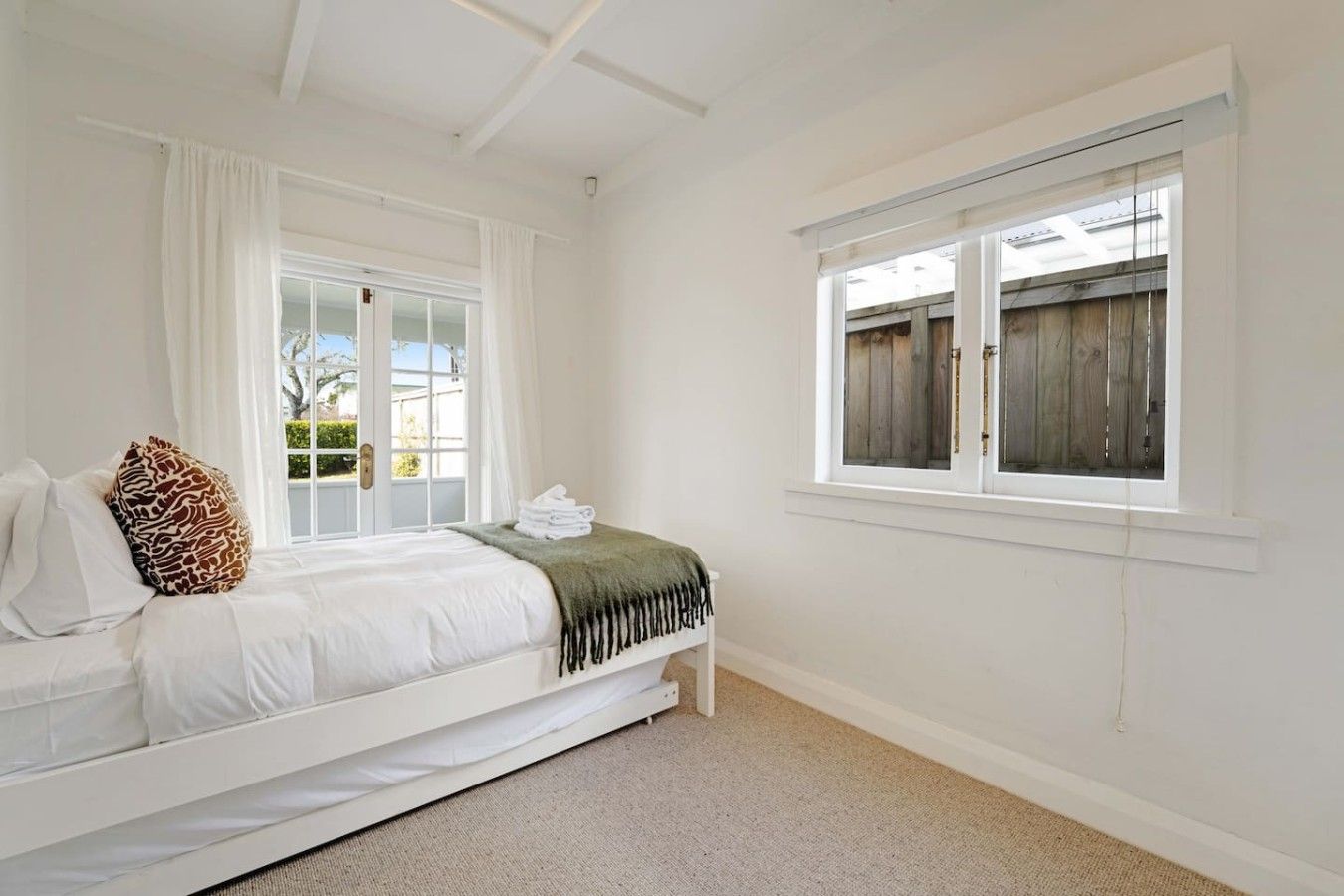A bedroom with a bed, a window, and a view of the outside.