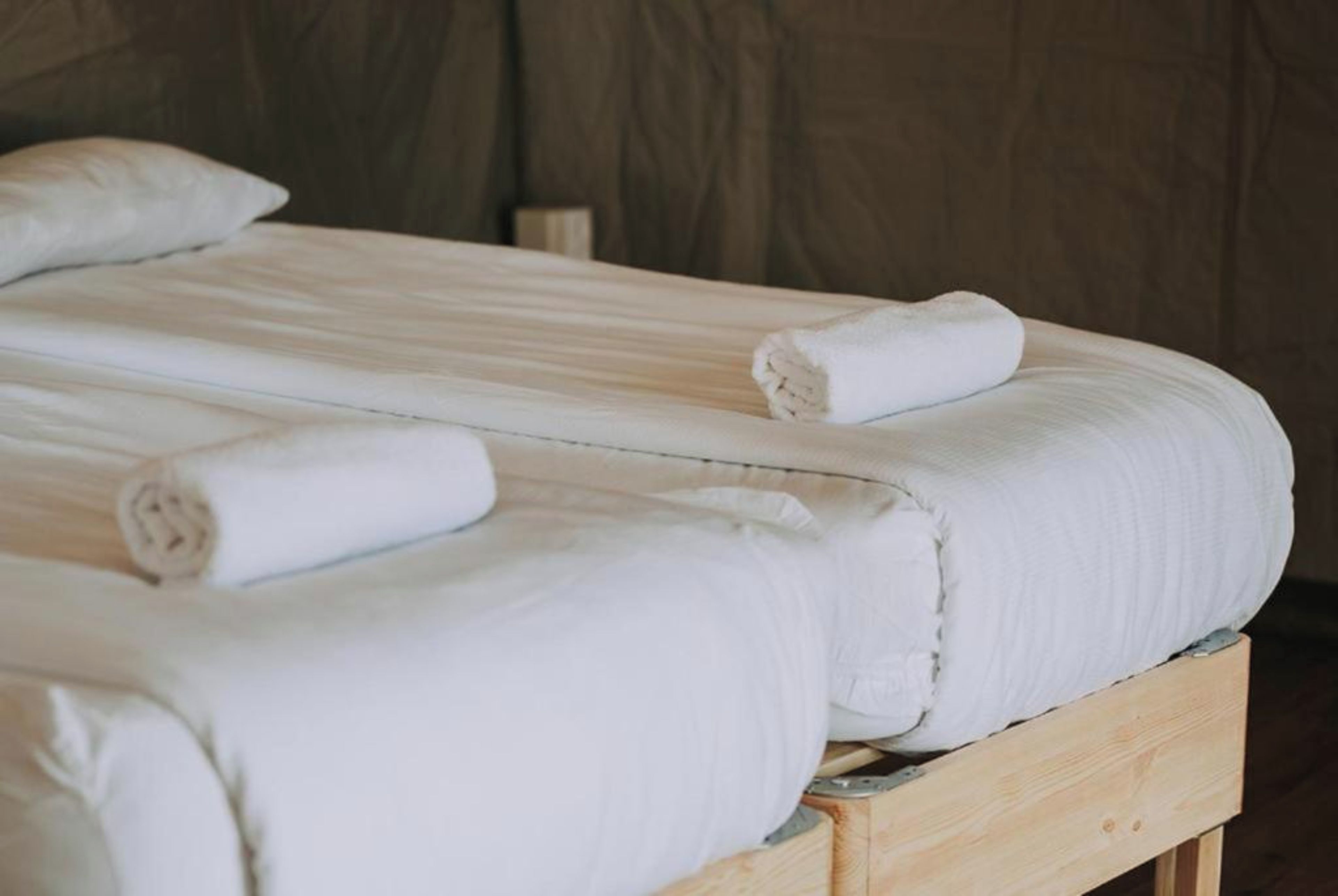 Una cama con sábanas blancas y toallas enrolladas.