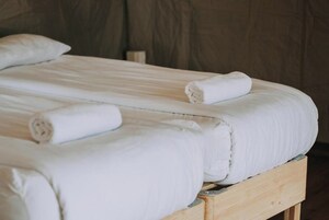 Una cama con sábanas blancas y toallas enrolladas.