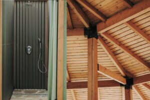 Techo de madera con vigas a la vista y una puerta metálica con diseño de rayas verticales.