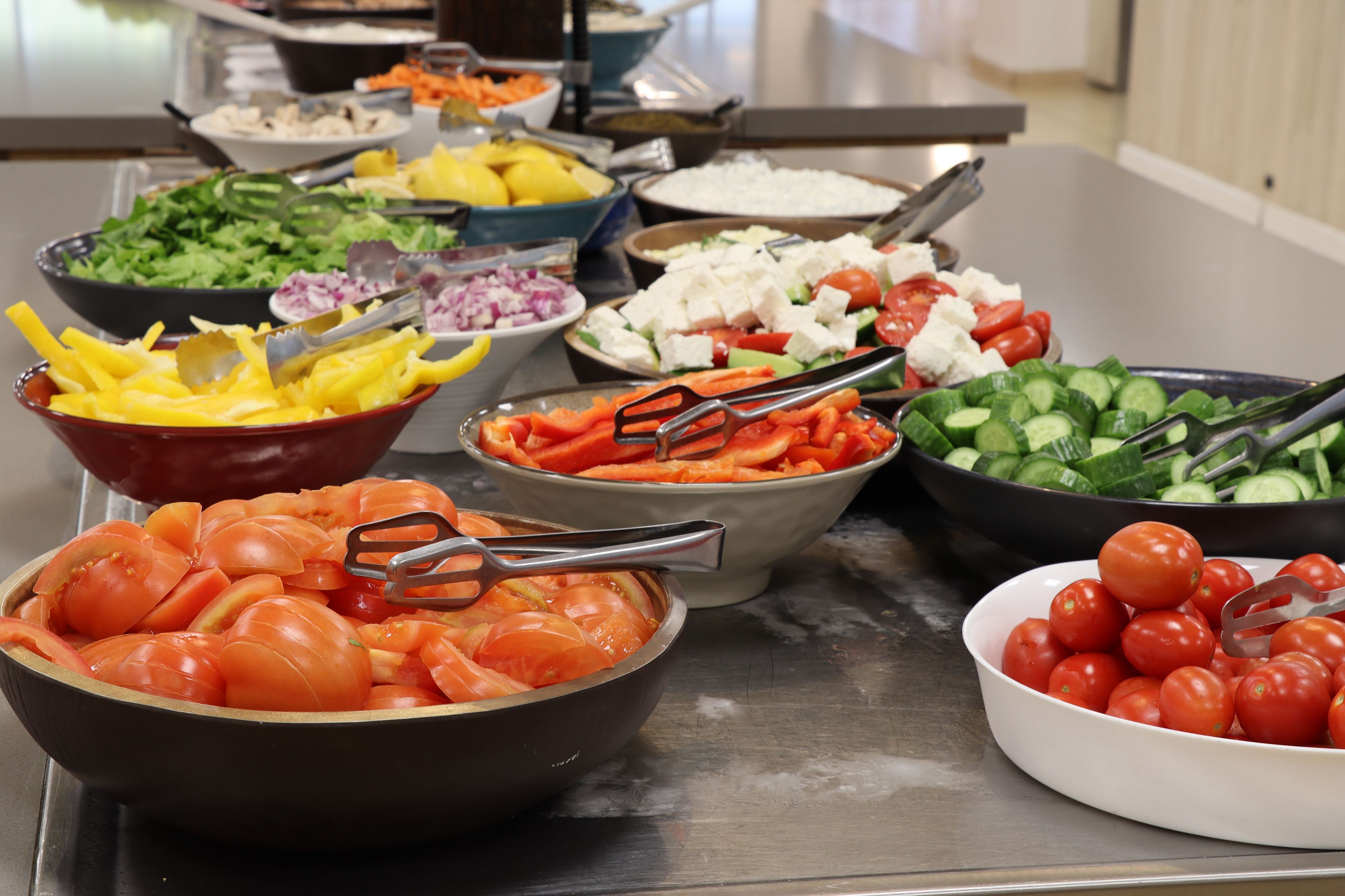 Una mesa de buffet con diversos alimentos, como tomates, pepinos y queso.