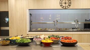 A buffet area with various food options and a clock on the wall.
