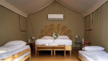 Una habitación con una cama, una mesita de noche, una lámpara y un equipo de aire acondicionado.