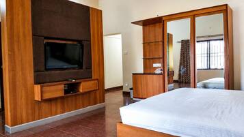 Una habitación de hotel moderna con una cama grande, un televisor montado en un panel de madera, un armario y un espejo.