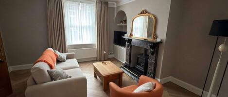 A living room with a sofa, armchair, fireplace, and a television.