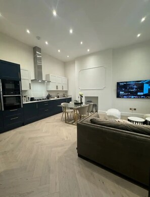 A modern kitchen with built-in appliances and a dining area with a table and chairs. - New listing discount on stylish 2 bedroom, 2 bathroom in Holland Park Kensington (London)