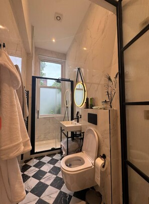 A bathroom with a checkered floor, a toilet, a sink, a mirror, and a towel rack. - New listing discount on stylish 2 bedroom, 2 bathroom in Holland Park Kensington (London)