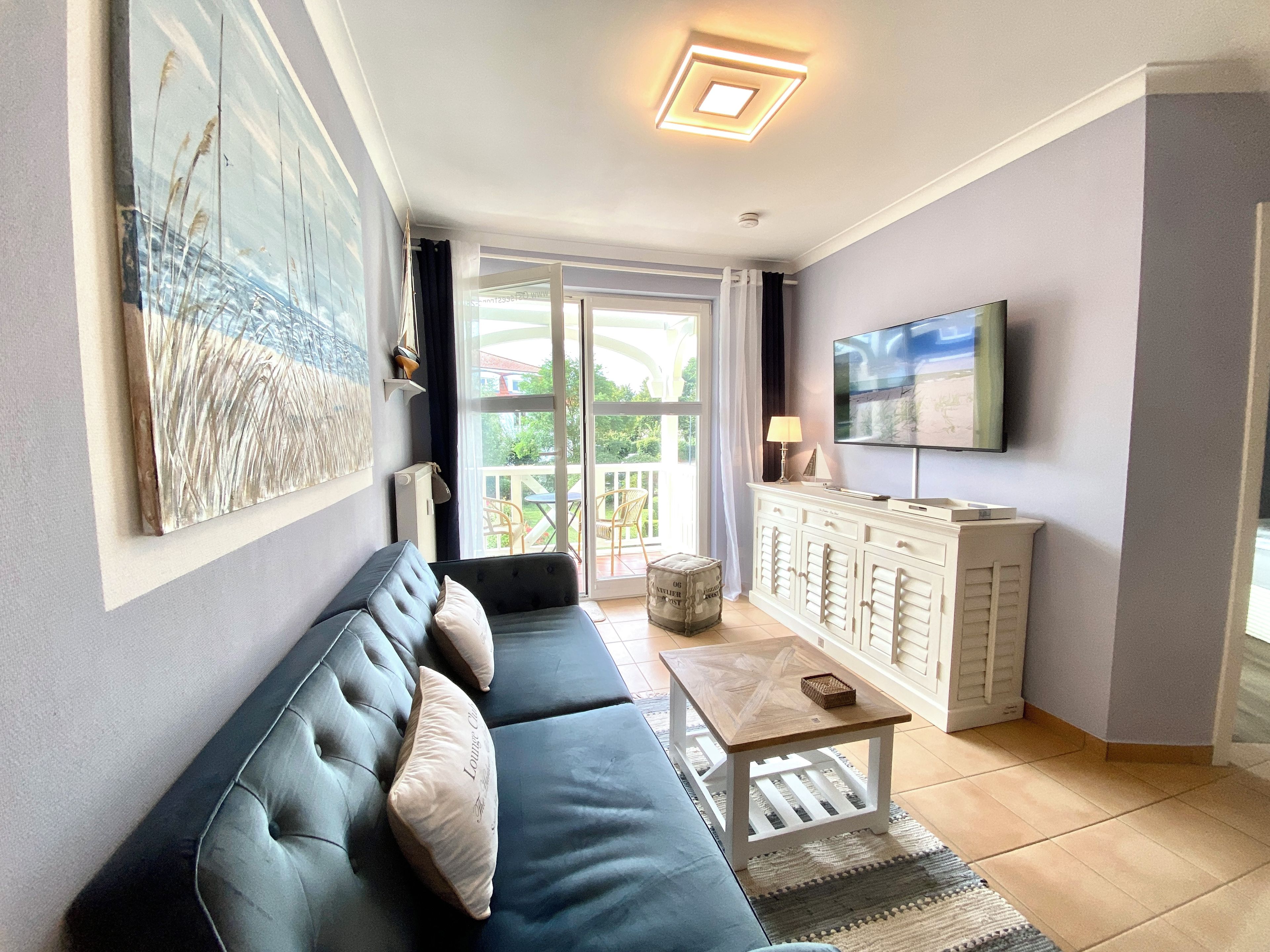 A living room with a sofa, television, cabinet, and artwork.