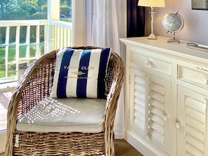 A wicker chair with a striped cushion, a white cabinet with drawers, and a globe on a table. - Ostseestrand-23, prime beachfront location, balcony, elevator, sauna (Kühlungsborn)