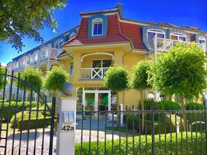 A yellow building with a red roof, white balconies, and a sign reading "Ostseestrasse". - Vrbo Property (Kühlungsborn)