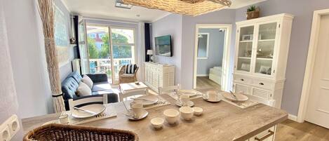 Cocina bien iluminada con una isla central, muebles de cocina blancos y una cesta de mimbre en la encimera.