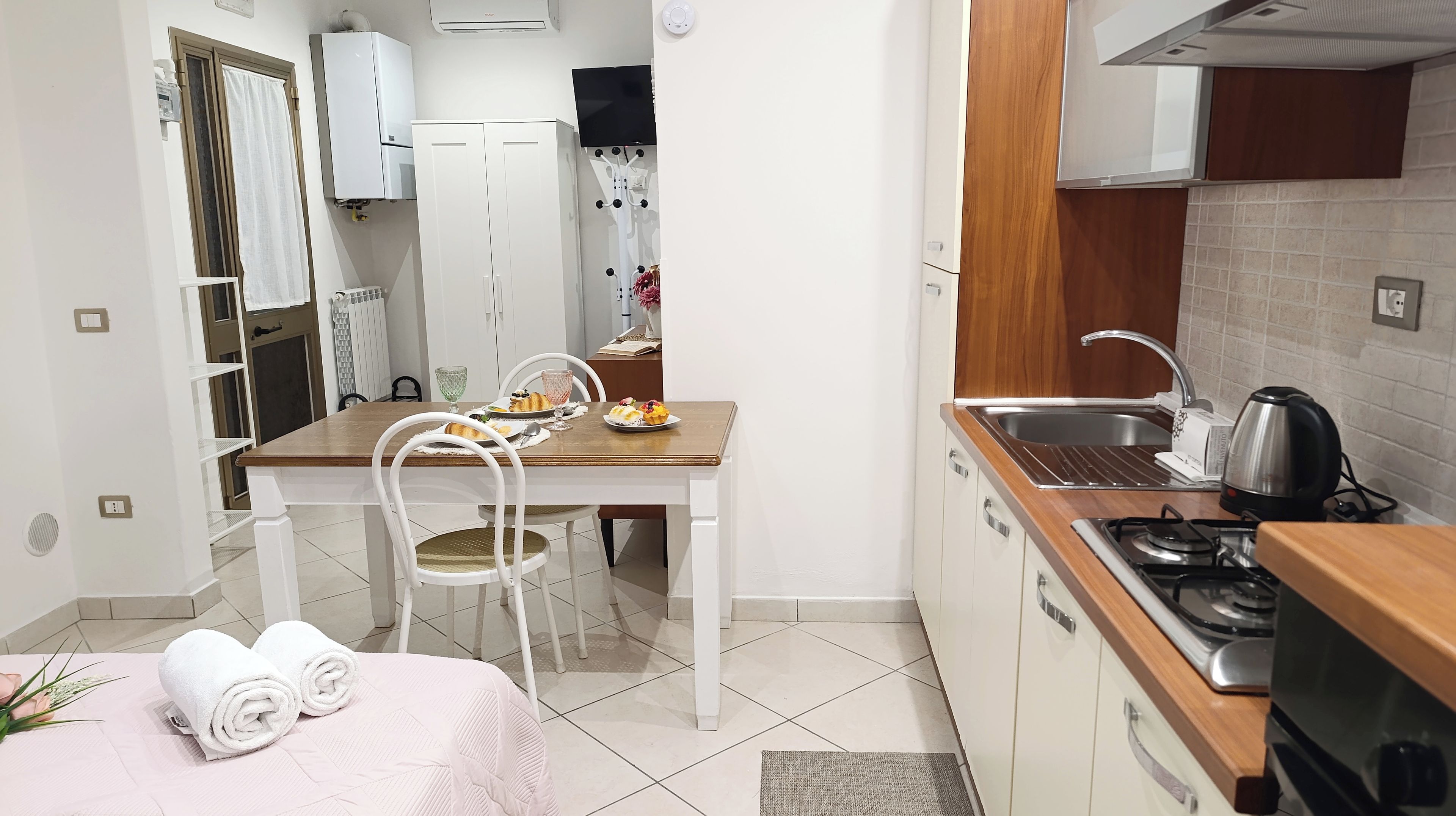 Uma cozinha compacta com área de refeições, armários brancos, fogão a gás e uma pia pequena.