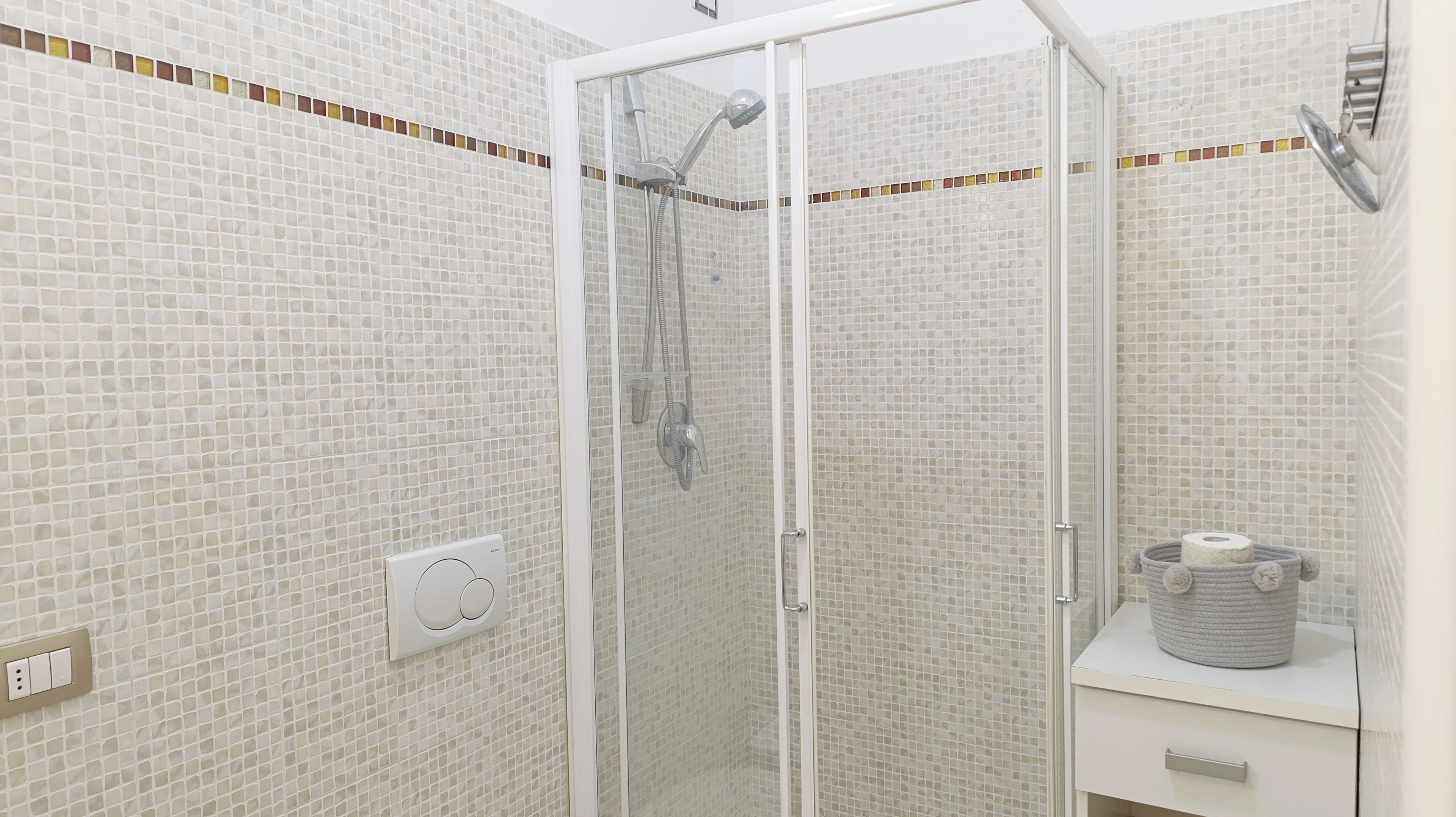 Een douche met een glazen deur, een handdoekhouder en een toiletrolhouder.