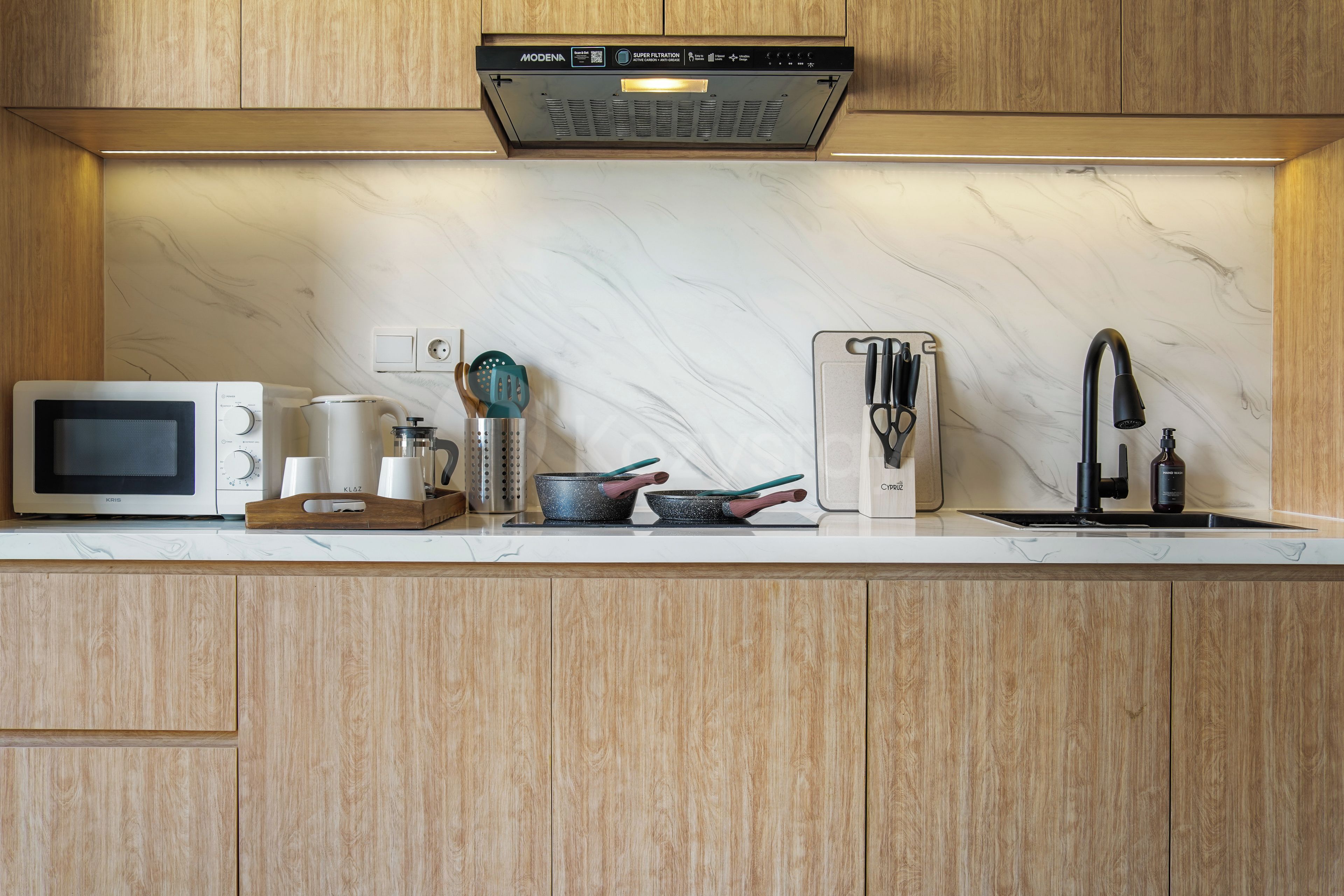 A modern kitchen with a built-in microwave, kettle, toaster, and sink.