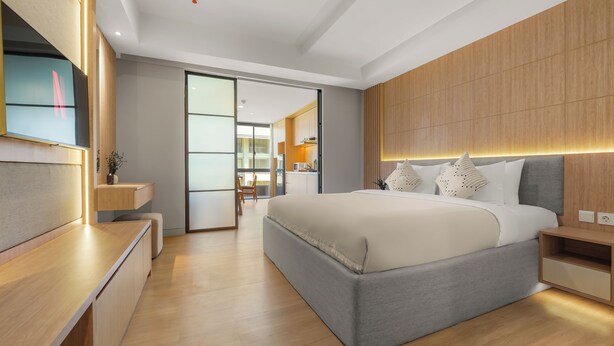A modern bedroom with a large bed, bedside tables, a desk, and a television. - Naya by Kozystay - Nusa Dua (Kuta)