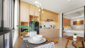 A modern kitchen with wooden cabinets, a microwave, and a Sharp refrigerator. - Naya by Kozystay - Nusa Dua (Kuta)