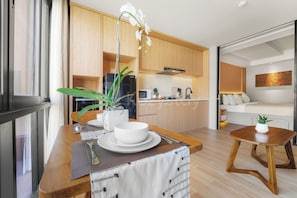A modern kitchen with wooden cabinets, a microwave, and a Sharp refrigerator. - Naya by Kozystay - Nusa Dua (Kuta)