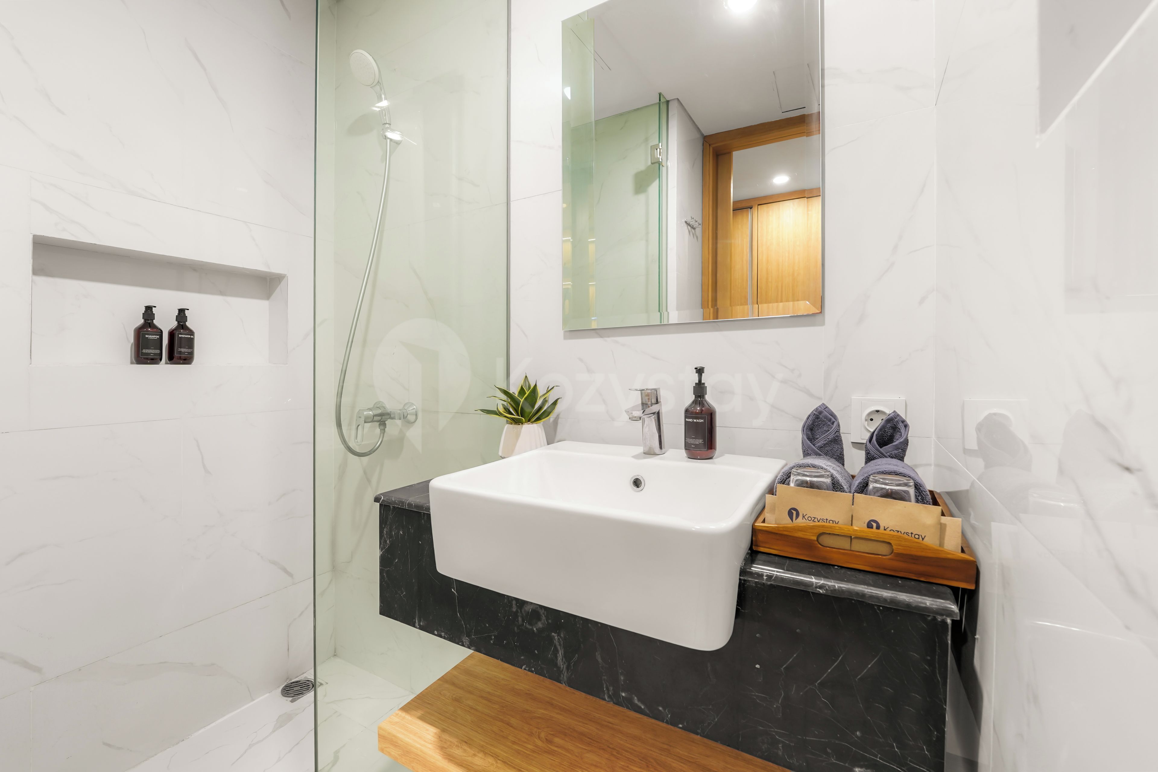 Une salle de bain moderne avec une douche à parois de verre, un lavabo blanc et un meuble-lavabo en bois.