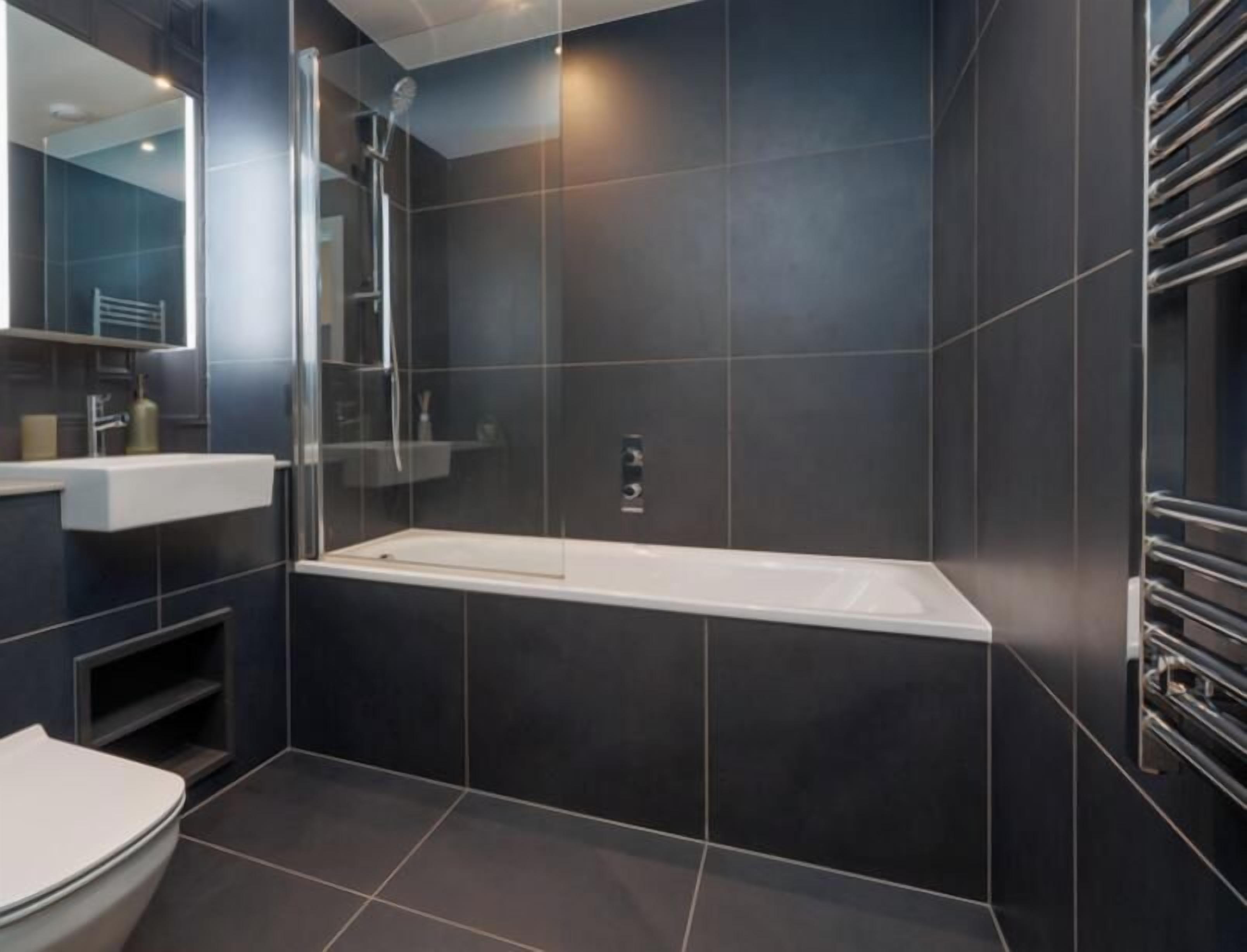 Une salle de bain moderne avec une douche à l’italienne, une baignoire blanche et un grand miroir.