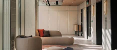 A modern lobby with a sofa, a chair, and a lamp.