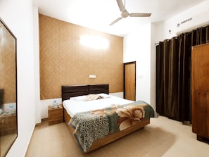 A bedroom with a bed, a nightstand, a ceiling fan, a wardrobe, and a mirror. - Premium Rooms For Corporates, Couples, Families, Students And Travelers (Ludhiana)