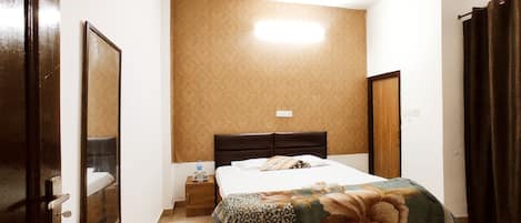Un dormitorio con cama, ventilador de techo, mesita de noche y una puerta.
