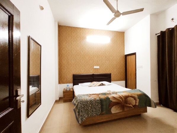 A bedroom with a bed, a ceiling fan, a nightstand, and a door.