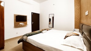 A bedroom with a bed, a television mounted on the wall, a door, and a ceiling fan. - Premium Rooms For Corporates, Couples, Families, Students And Travelers (Ludhiana)