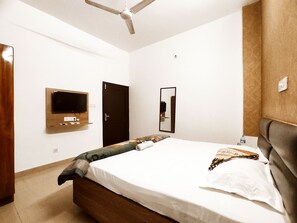A bedroom with a bed, a television mounted on the wall, a door, and a ceiling fan. - Premium Rooms For Corporates, Couples, Families, Students And Travelers (Ludhiana)